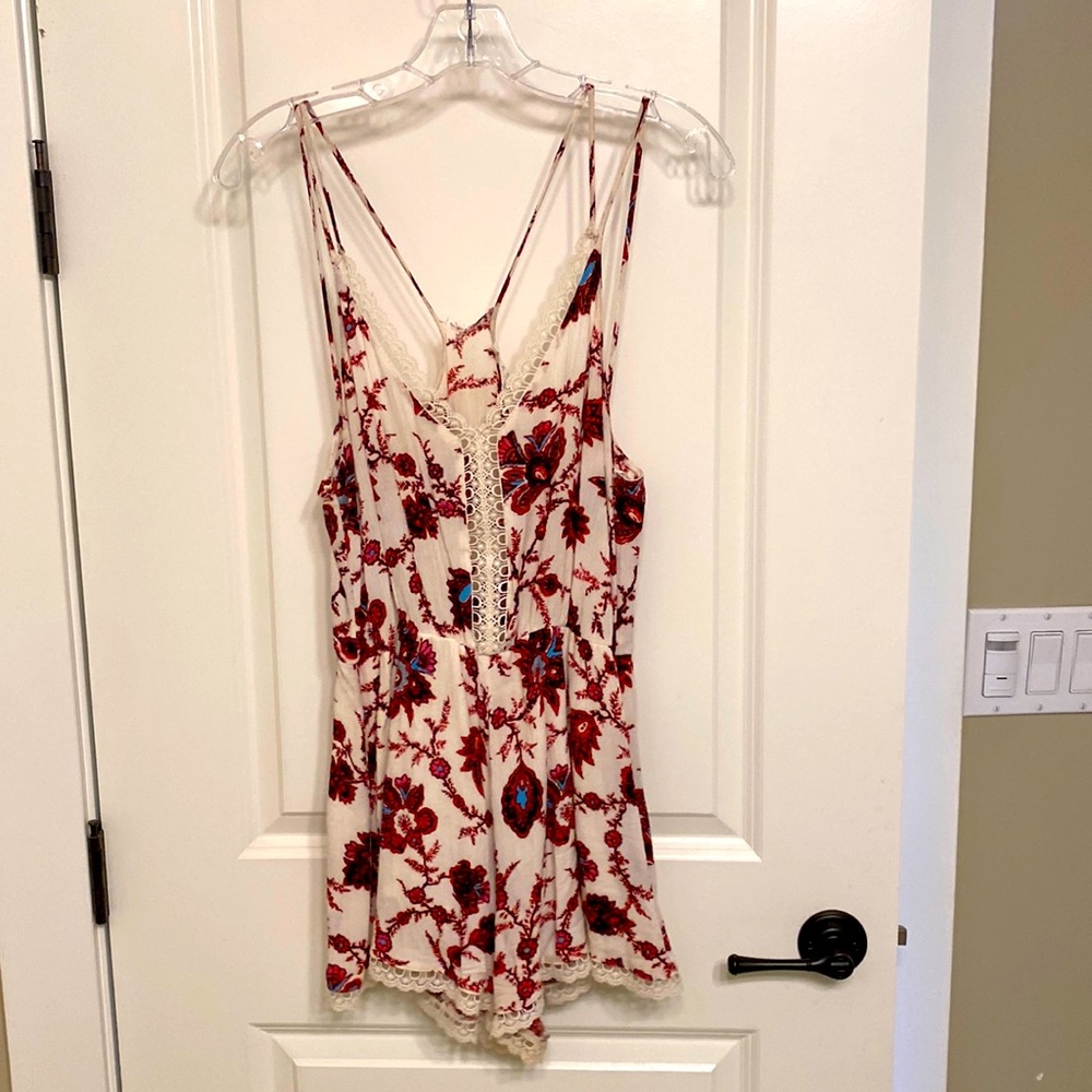 Small flowy white romper with pink floral pattern throughout. Some lace trimming